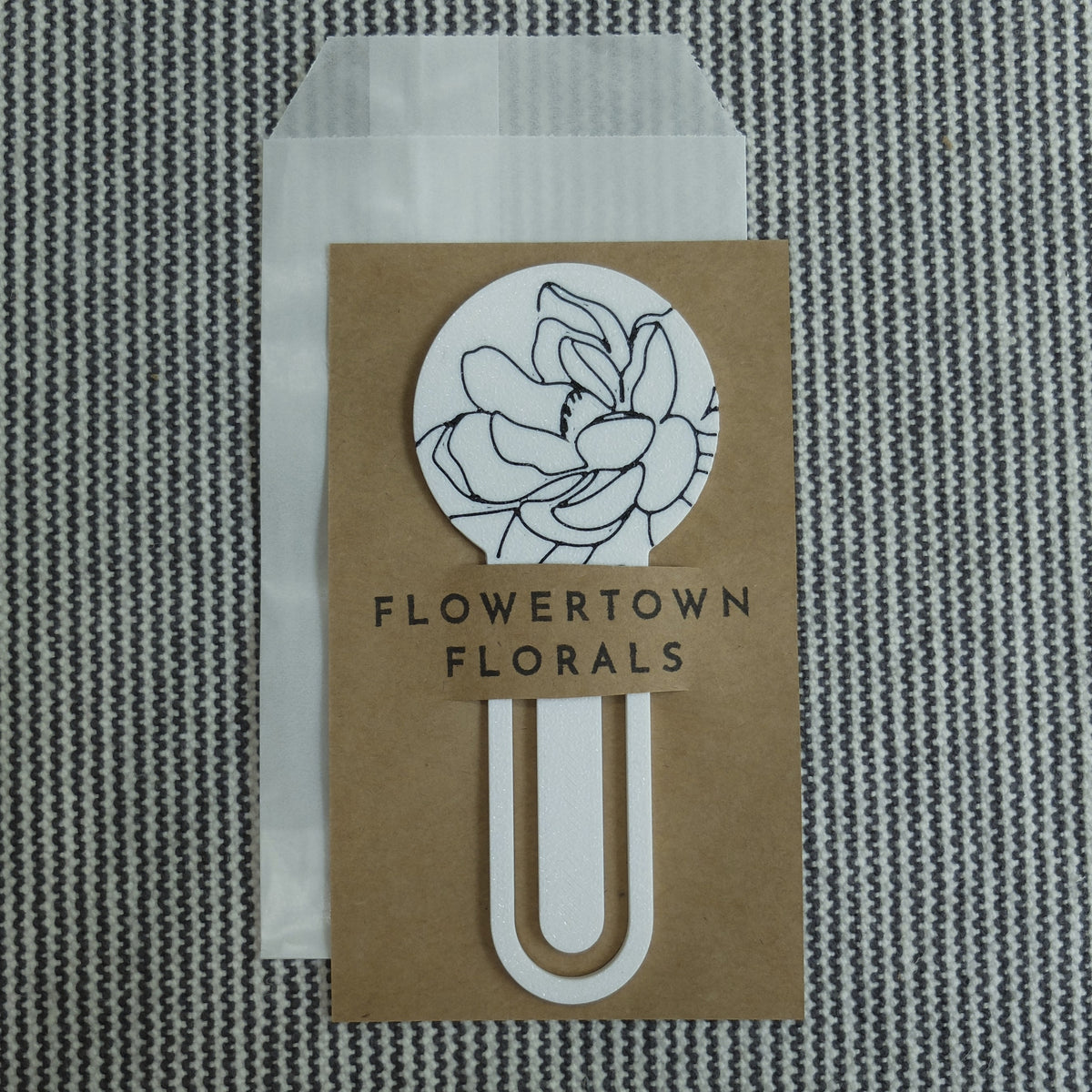 a white magnolia 3d printed bookmark presented on a kraft card with a glassine bag